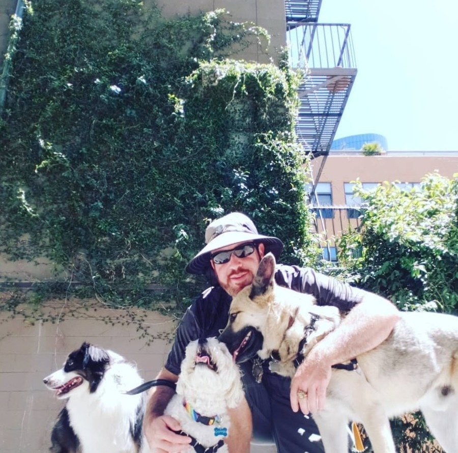 Greg kneeling with his city crew, three happy dogs